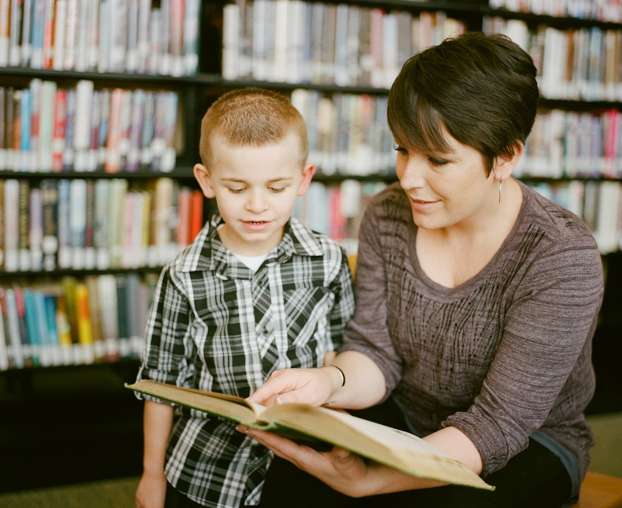 A coach reading with a young student in a library